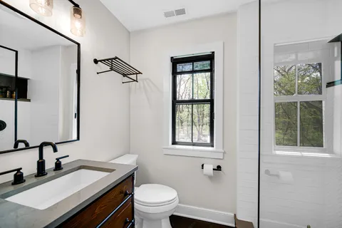 a bathroom with a granite countertop sink toilet a mirror and shower