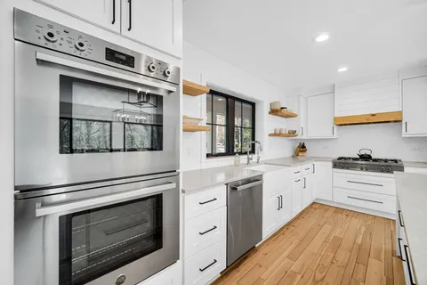 a kitchen with stainless steel appliances white cabinets and wooden floor
