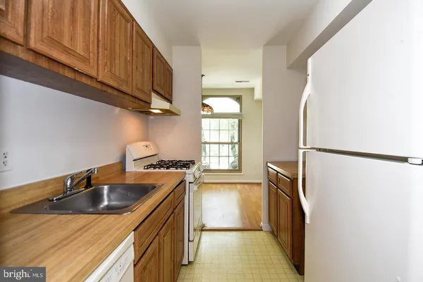 a kitchen with stainless steel appliances granite countertop a sink a stove a refrigerator a washer and dryer with wooden floor