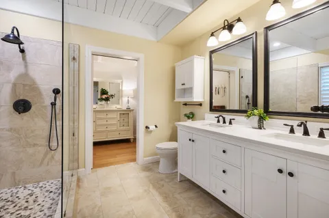 a bathroom with a double vanity sink toilet mirror and shower