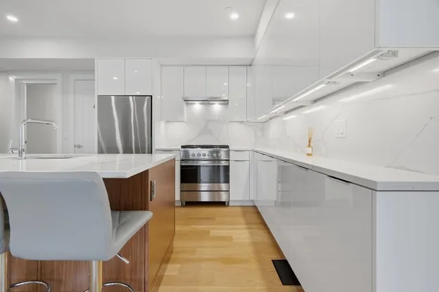 a kitchen with stainless steel appliances a stove a refrigerator and a sink with wooden floor