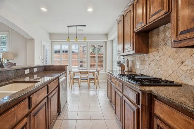 a kitchen with granite countertop a sink a stove and a wooden cabinets