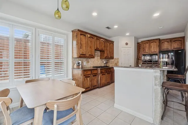 a kitchen with kitchen island granite countertop a stove top oven a sink a dining table and chairs