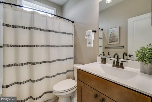 a bathroom with a double vanity sink a toilet and shower