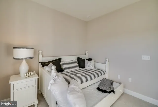 a bedroom with bed and a lamp on dresser