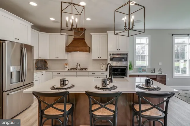 a large kitchen with stainless steel appliances granite countertop a stove a refrigerator a sink and a fireplace with wooden floor