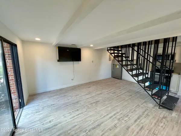 a view of an empty room with wooden floor and staircase