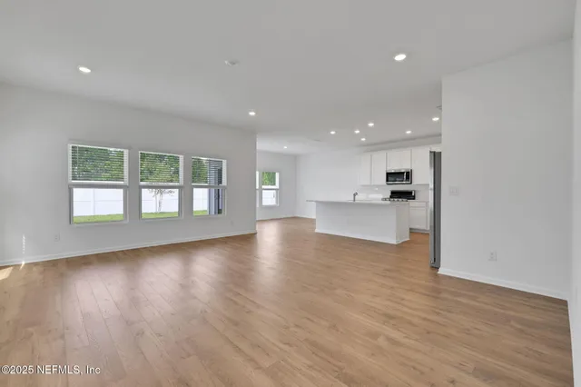 a large kitchen with stainless steel appliances granite countertop a large counter top and a stove with wooden floor