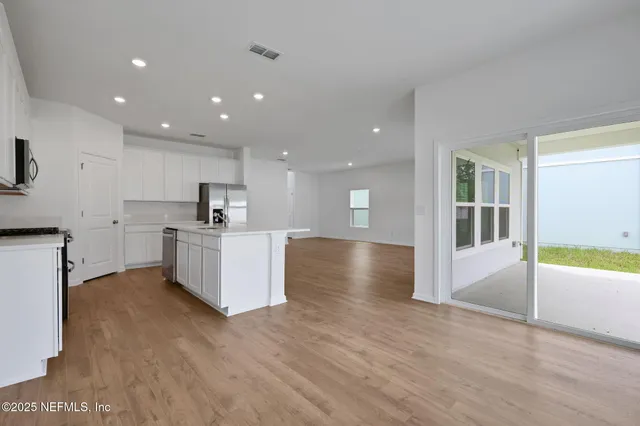 a kitchen with stainless steel appliances a refrigerator a stove top oven a sink and white cabinets