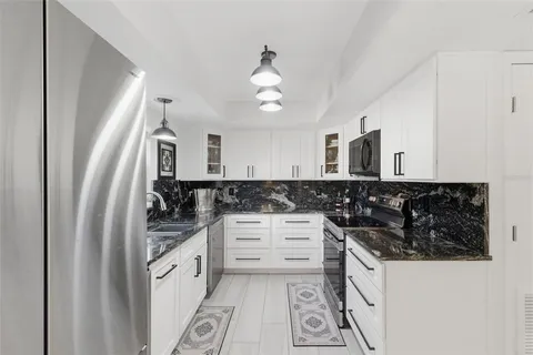 a kitchen with granite countertop white cabinets and stainless steel appliances