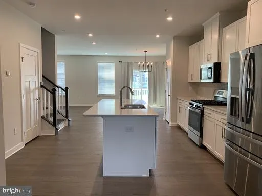 a open kitchen with stainless steel appliances kitchen island granite countertop a refrigerator a stove and a sink with wooden floor