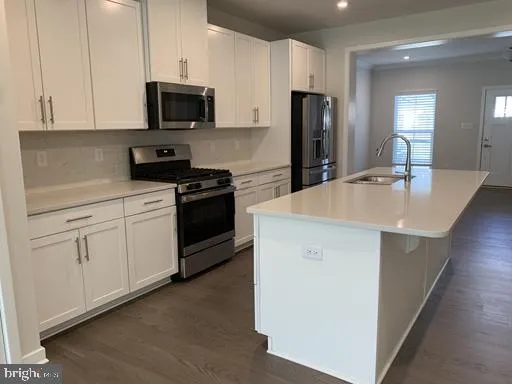 a kitchen with stainless steel appliances white cabinets a sink a stove a refrigerator and microwave