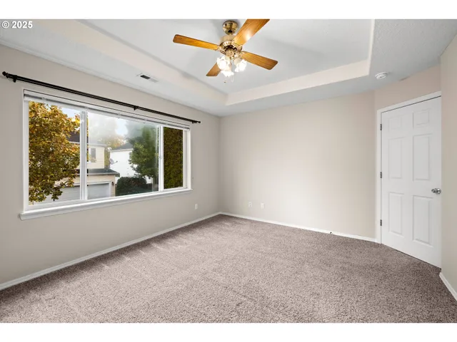 a view of an empty room with window and a ceiling fan