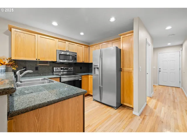 a kitchen with stainless steel appliances granite countertop a refrigerator a sink a stove a microwave and wooden cabinets