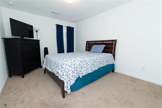 a bedroom with a bed and a flat tv screen on a dresser