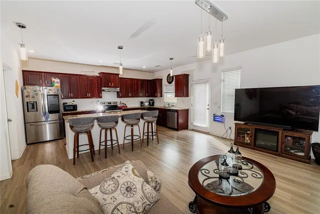 a living room with stainless steel appliances furniture a rug and a kitchen view