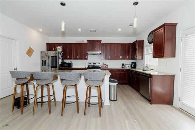 a kitchen with stainless steel appliances granite countertop a table chairs microwave and sink