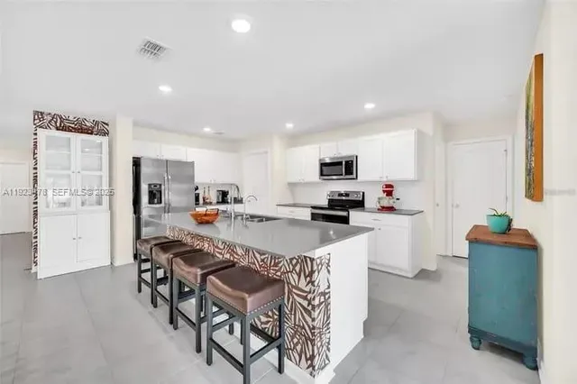 a kitchen with stainless steel appliances kitchen island granite countertop a refrigerator and a stove top oven