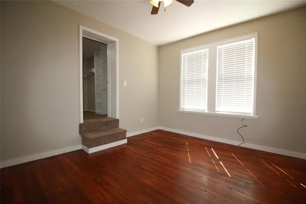 an empty room with wooden floor and fan