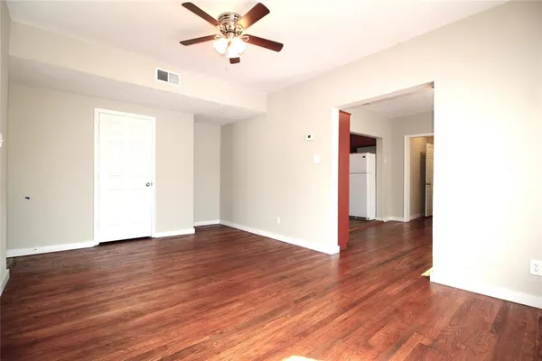 a view of an empty room with window and wooden floor