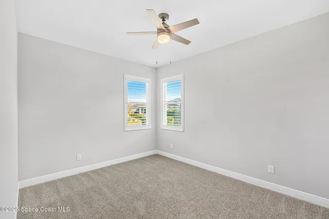 an empty room with a window and a fan