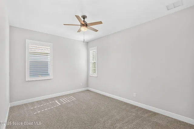 a view of a big room with a ceiling fan and windows