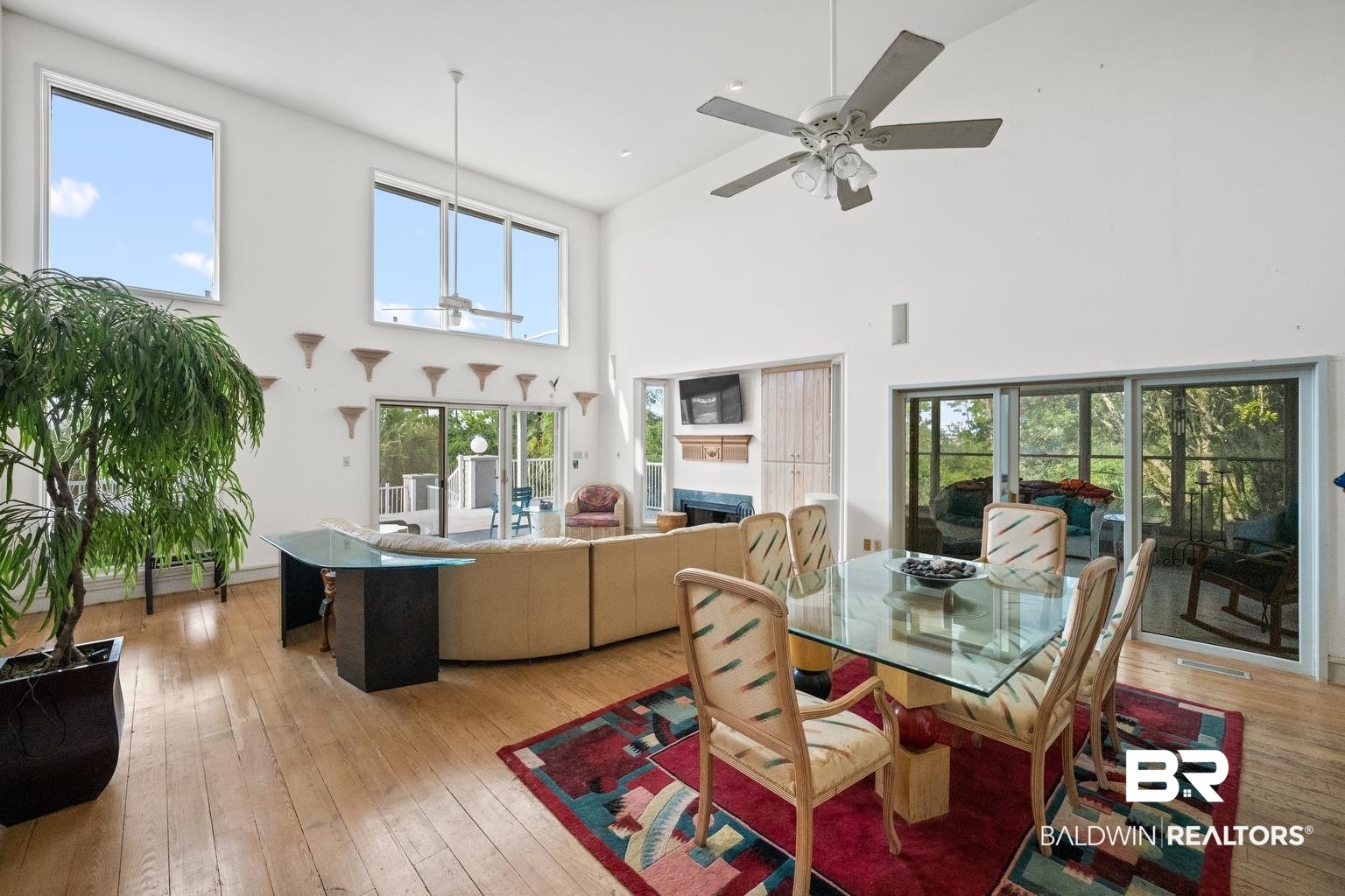 29255 Ono Boulevard Orange Beach, AL 36561 - Photo 17 of 43 Dining room with high vaulted ceiling, ceiling fan, a fireplace, and light wood finished floors