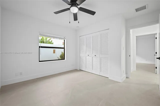 an empty room with windows and fan