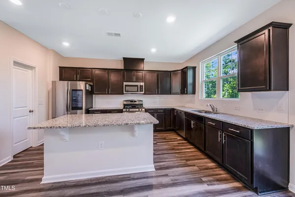 a large kitchen with stainless steel appliances kitchen island granite countertop a stove and a sink