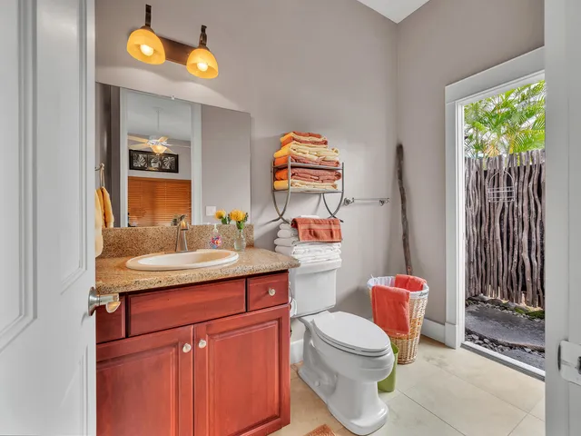 a bathroom with a granite countertop sink vanity mirror and toilet