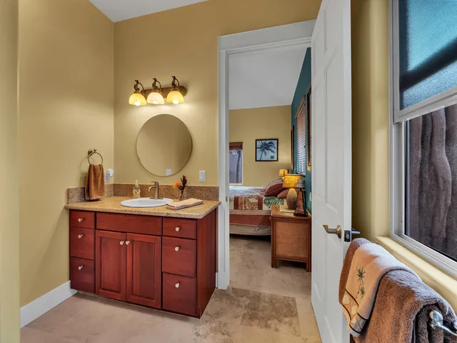 a en suite bathroom with a granite countertop sink and a mirror
