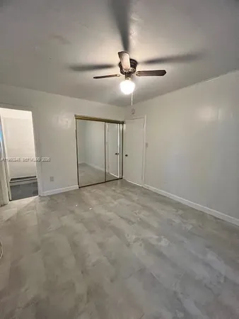an empty room with a ceiling fan and windows