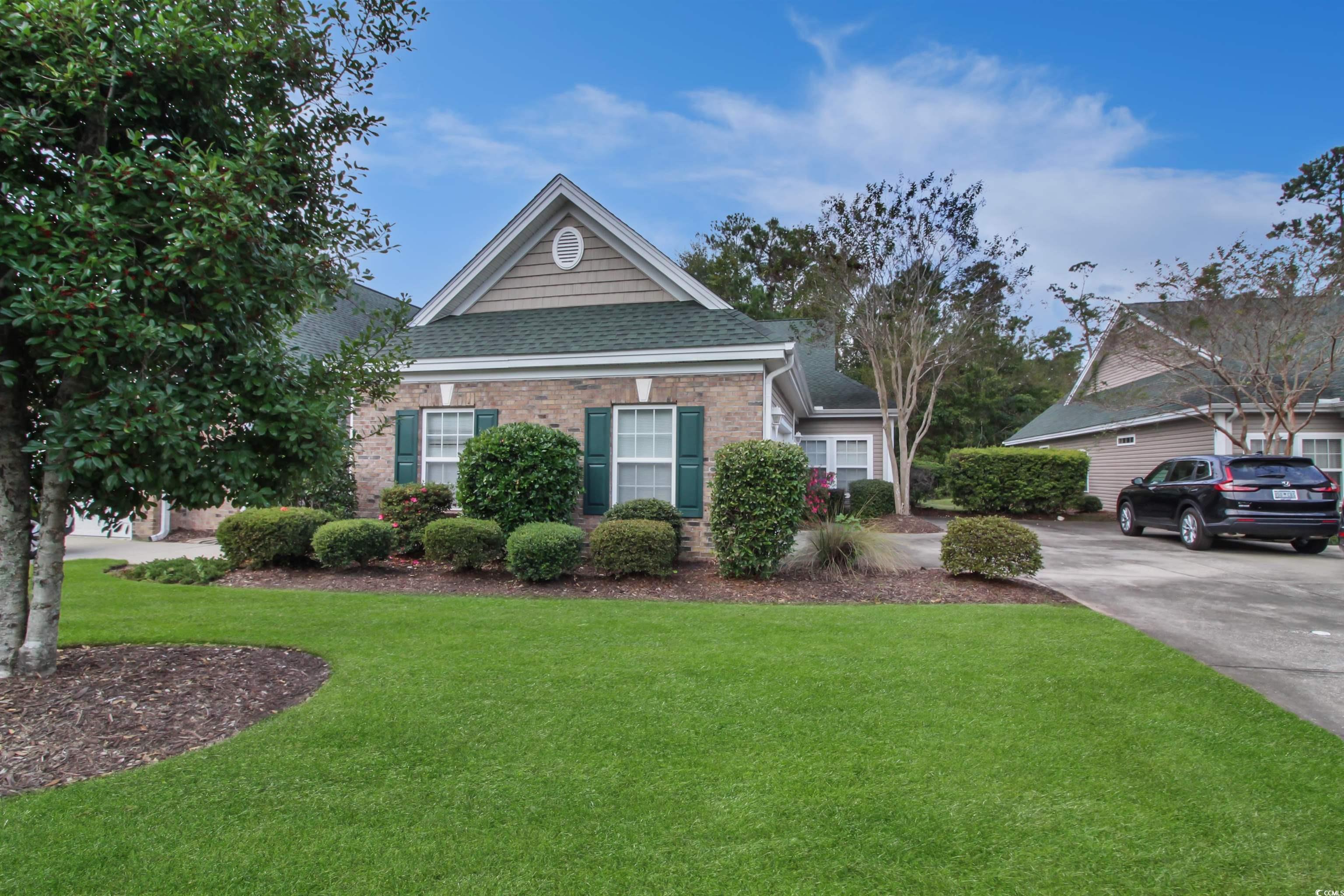 301 Nut Hatch Lane, Unit D Murrells Inlet, SC 29576 - Photo 32 of 40 View of side of home featuring brick siding, a yard, and a shingled roof