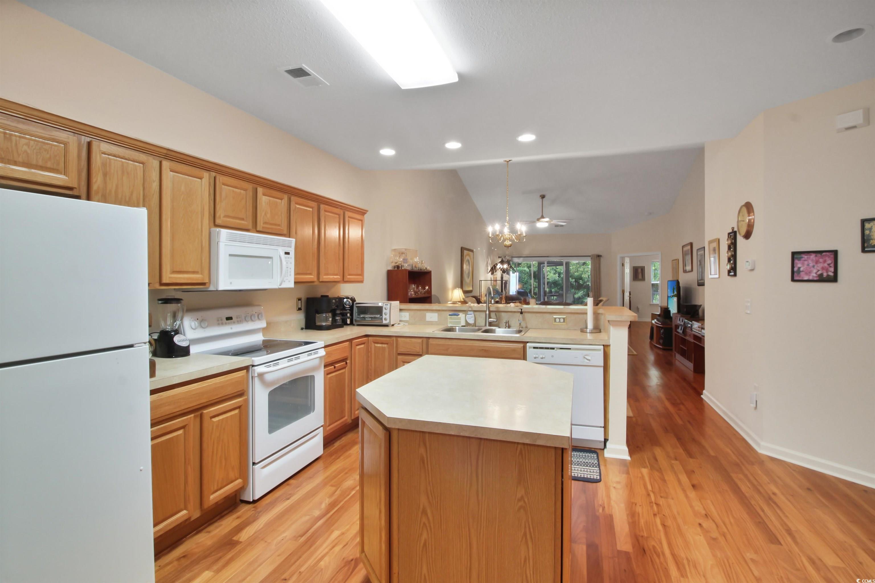 301 Nut Hatch Lane, Unit D Murrells Inlet, SC 29576 - Photo 6 of 40 Kitchen with white appliances, vaulted ceiling, a peninsula, light wood-style flooring, and light countertops