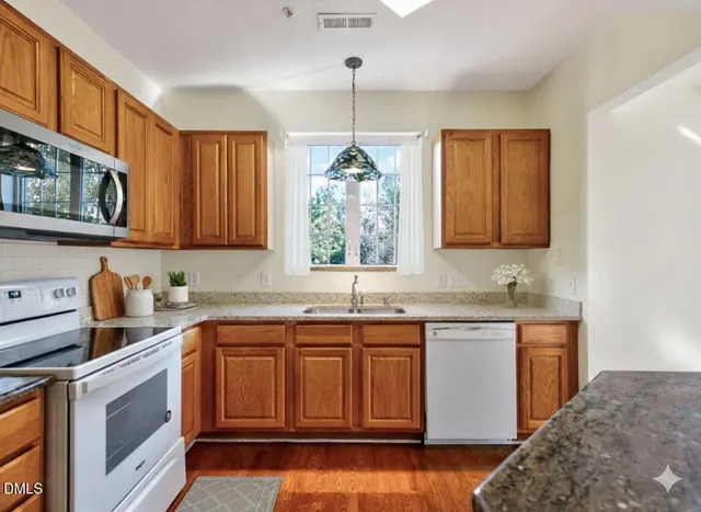 a kitchen with stainless steel appliances granite countertop a sink a stove and cabinets