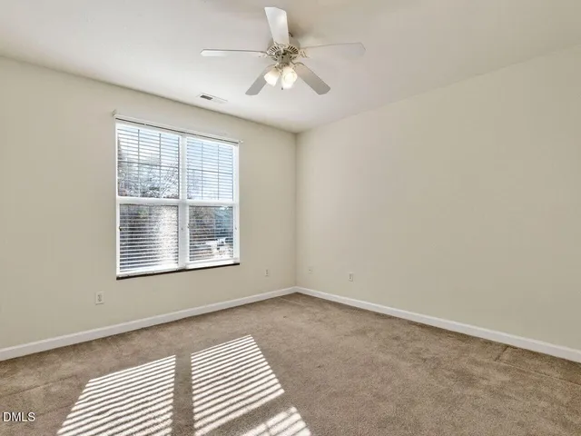 an empty room with chandelier fan and windows