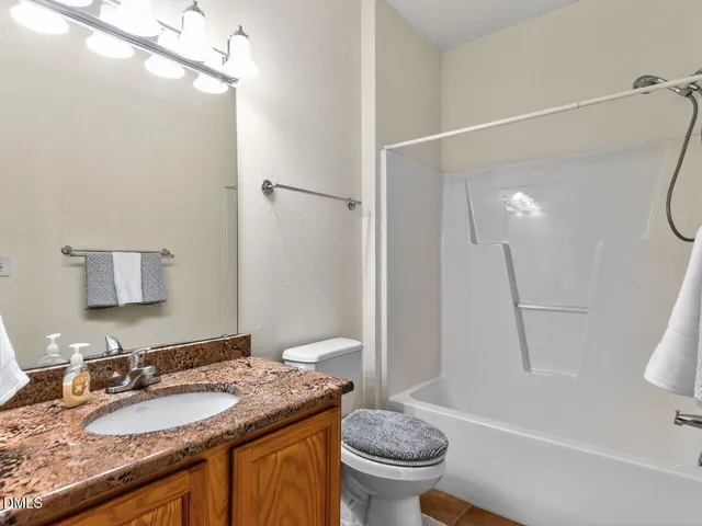 a bathroom with a granite countertop sink a toilet a mirror and shower
