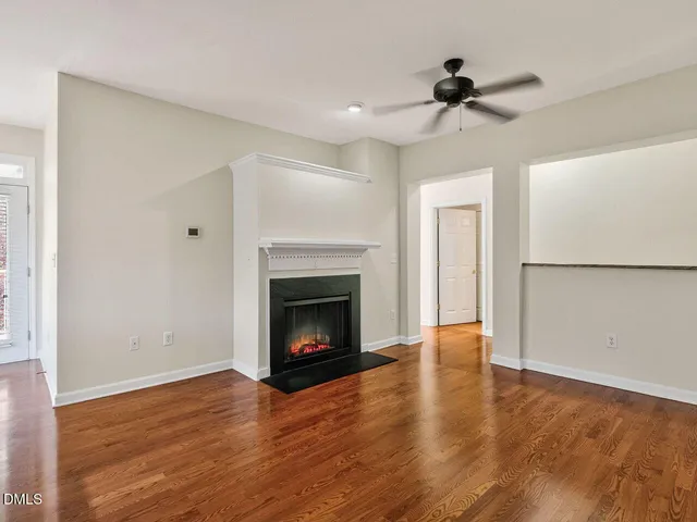 a view of an empty room with wooden floor fireplace and a window