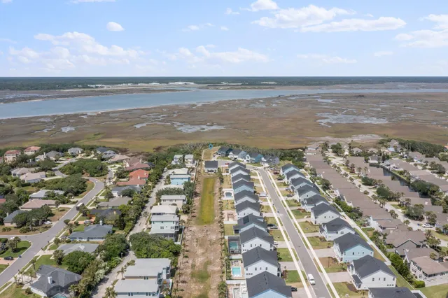 an aerial view of ocean and residential houses with outdoor space