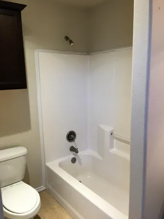 a white toilet sitting next to a bath tub