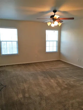 en empty room with windows and chandelier fan