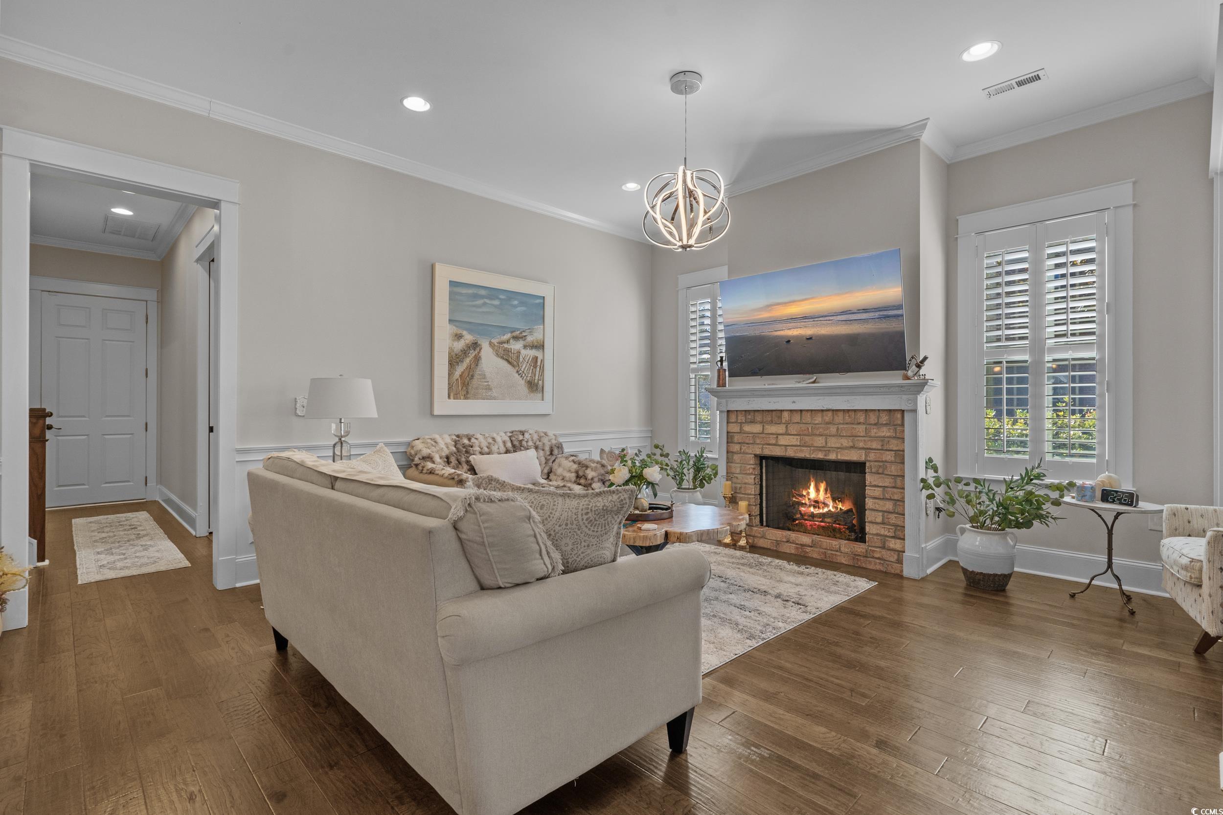927 Iris Street Myrtle Beach, SC 29577 - Photo 11 of 40 Living area with crown molding, a brick fireplace, recessed lighting, dark wood-style flooring, and a chandelier