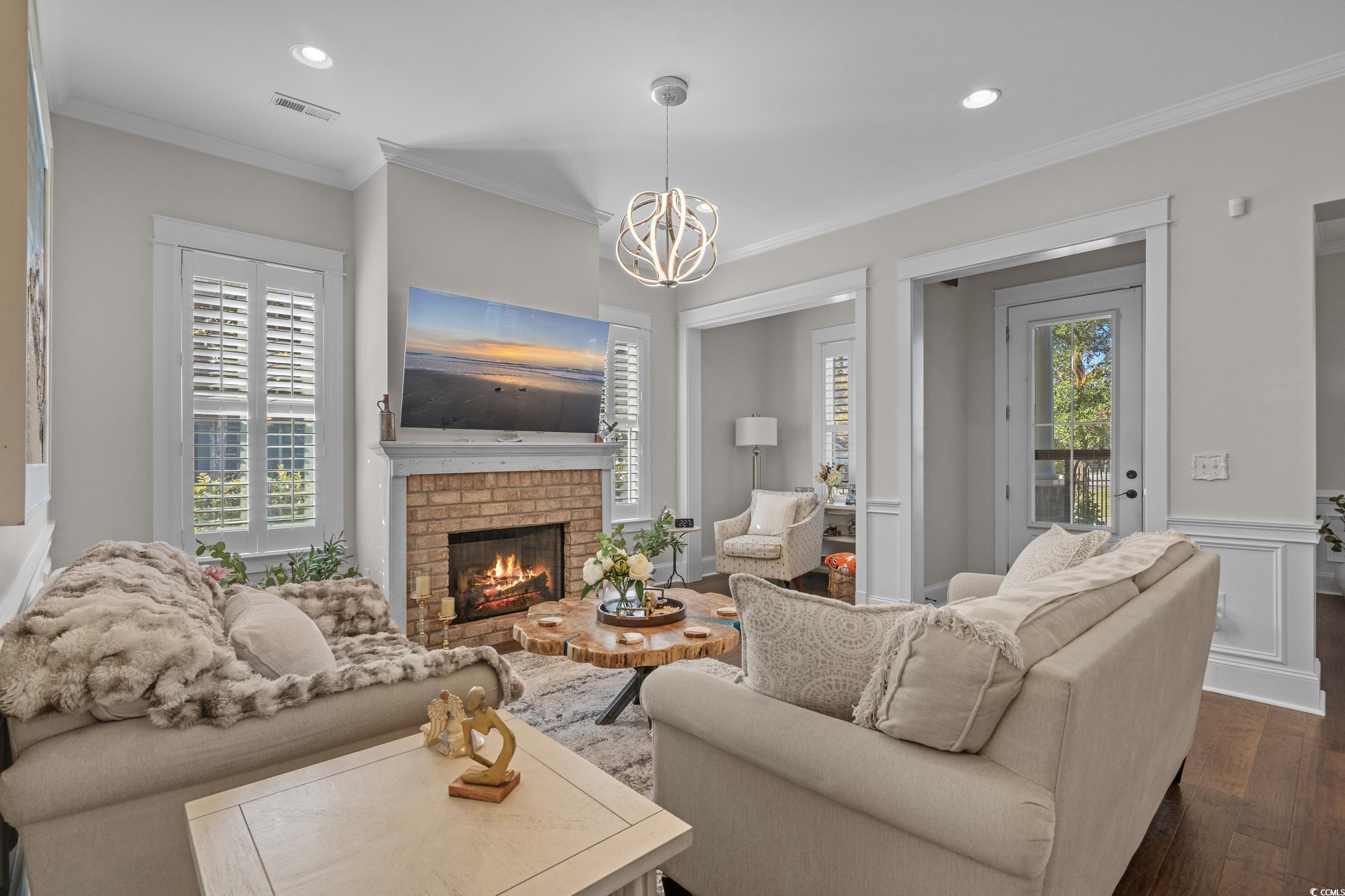 927 Iris Street Myrtle Beach, SC 29577 - Photo 12 of 40 Living area with ornamental molding, dark wood finished floors, a fireplace, recessed lighting, and a chandelier