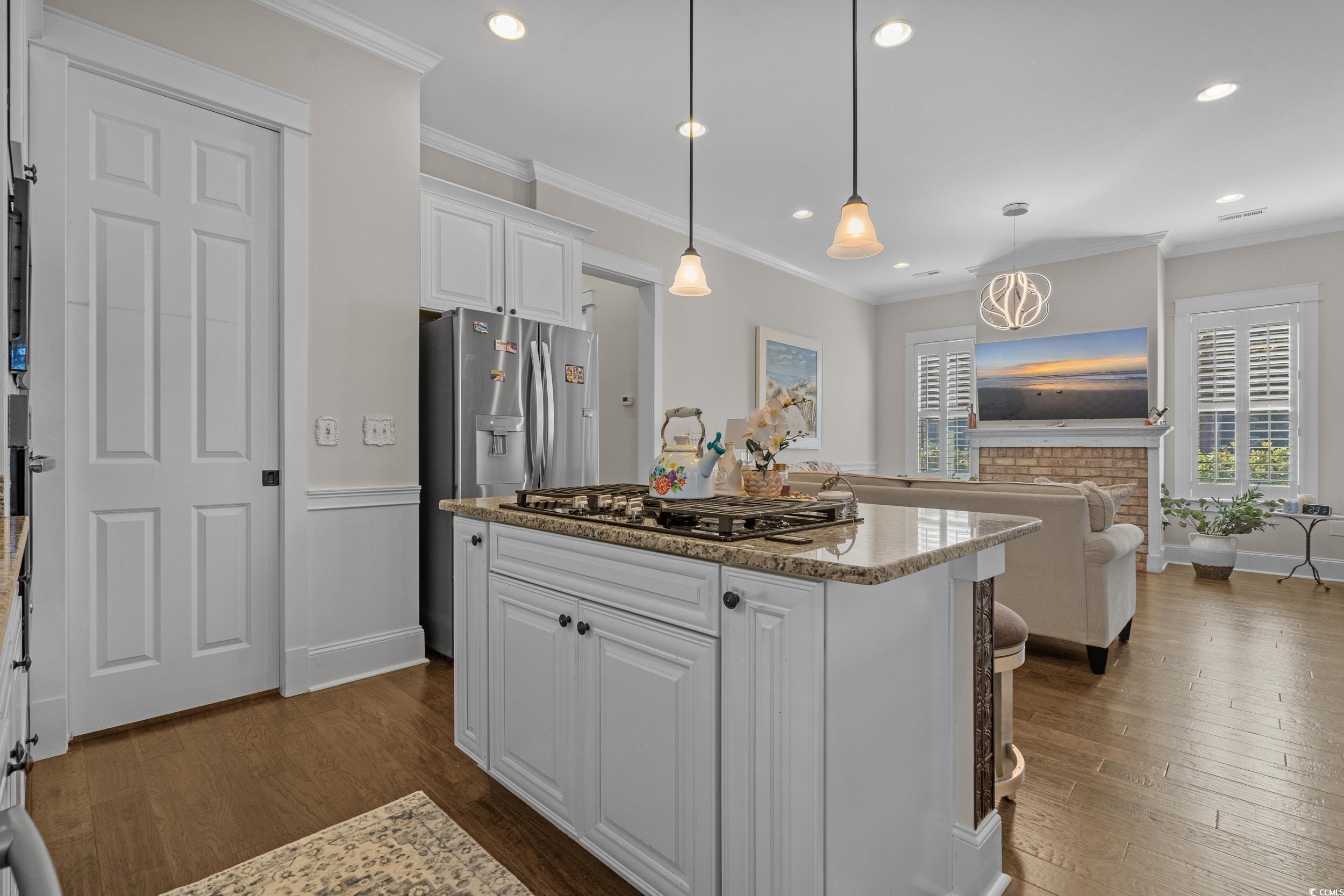 927 Iris Street Myrtle Beach, SC 29577 - Photo 17 of 40 Kitchen with white cabinetry, light stone counters, ornamental molding, pendant lighting, and dark wood-style flooring