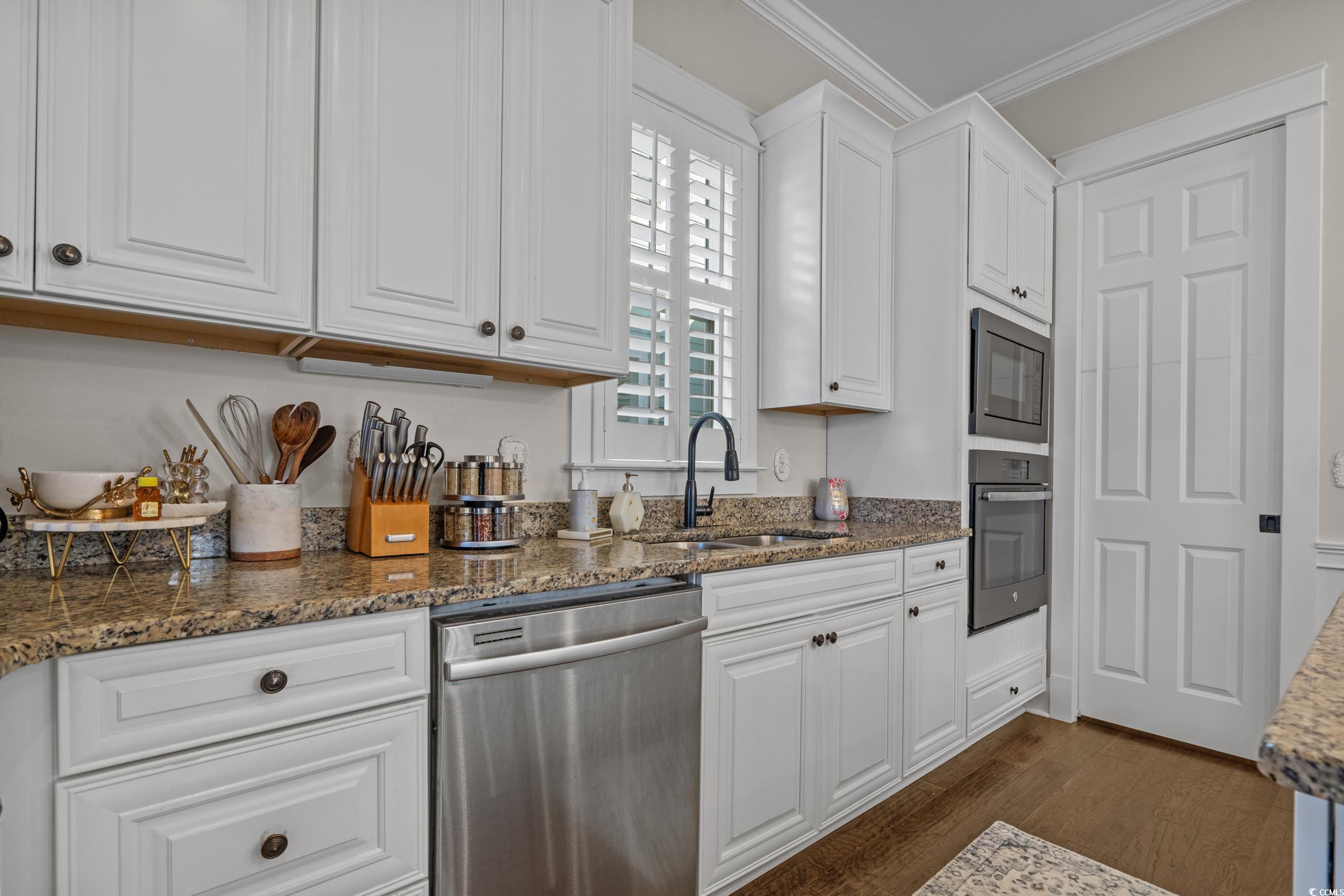 927 Iris Street Myrtle Beach, SC 29577 - Photo 18 of 40 Kitchen featuring dark stone counters, stainless steel appliances, white cabinets, and ornamental molding