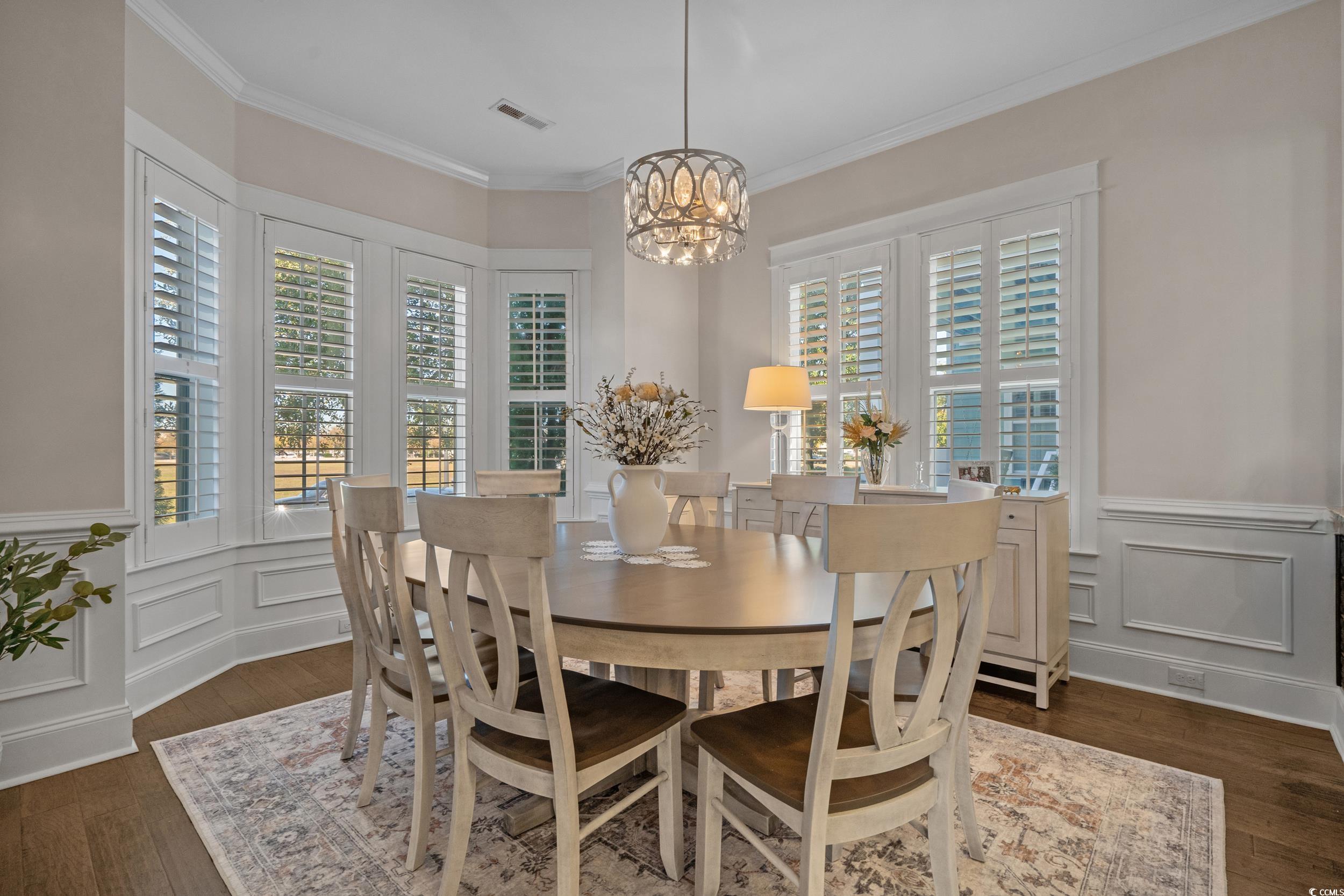 927 Iris Street Myrtle Beach, SC 29577 - Photo 20 of 40 Dining space with wainscoting, ornamental molding, a decorative wall, dark wood-style flooring, and a chandelier