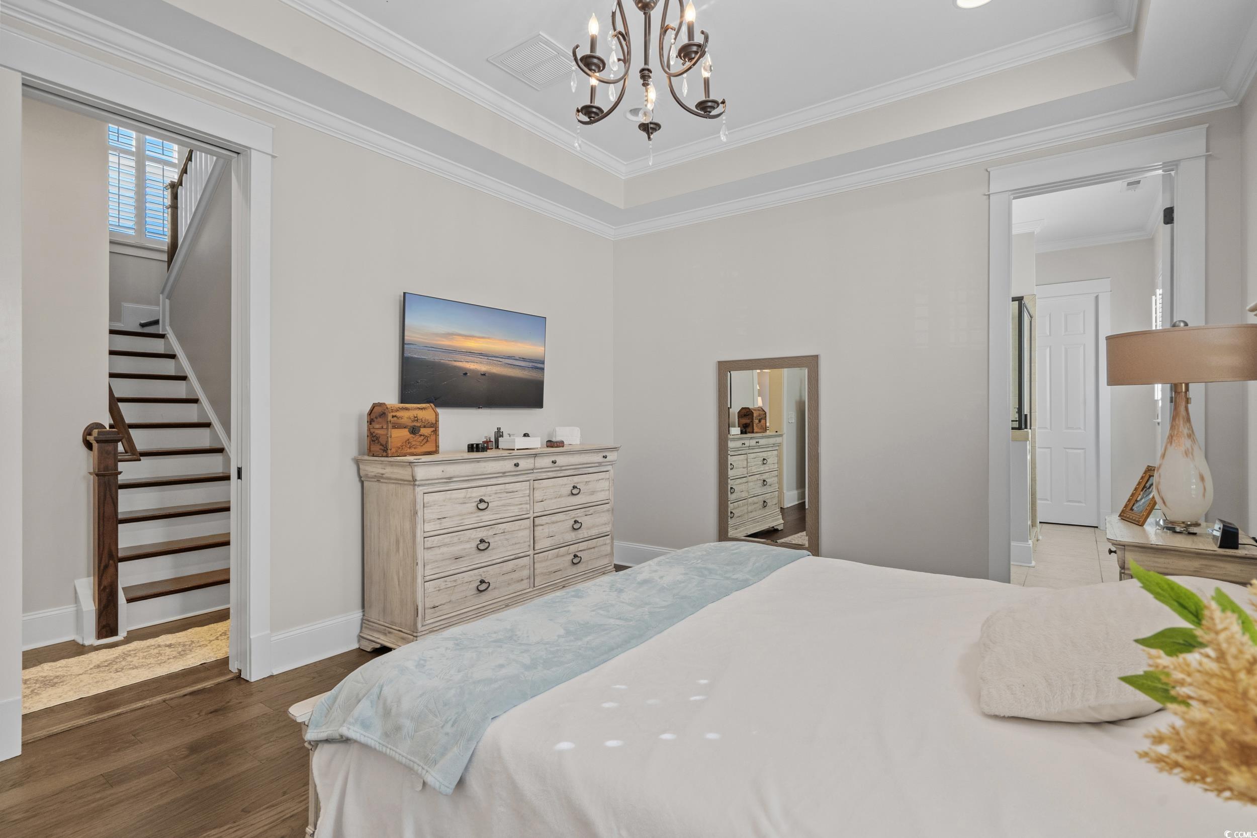 927 Iris Street Myrtle Beach, SC 29577 - Photo 27 of 40 Bedroom with a raised ceiling, dark wood-style floors, a chandelier, and ornamental molding
