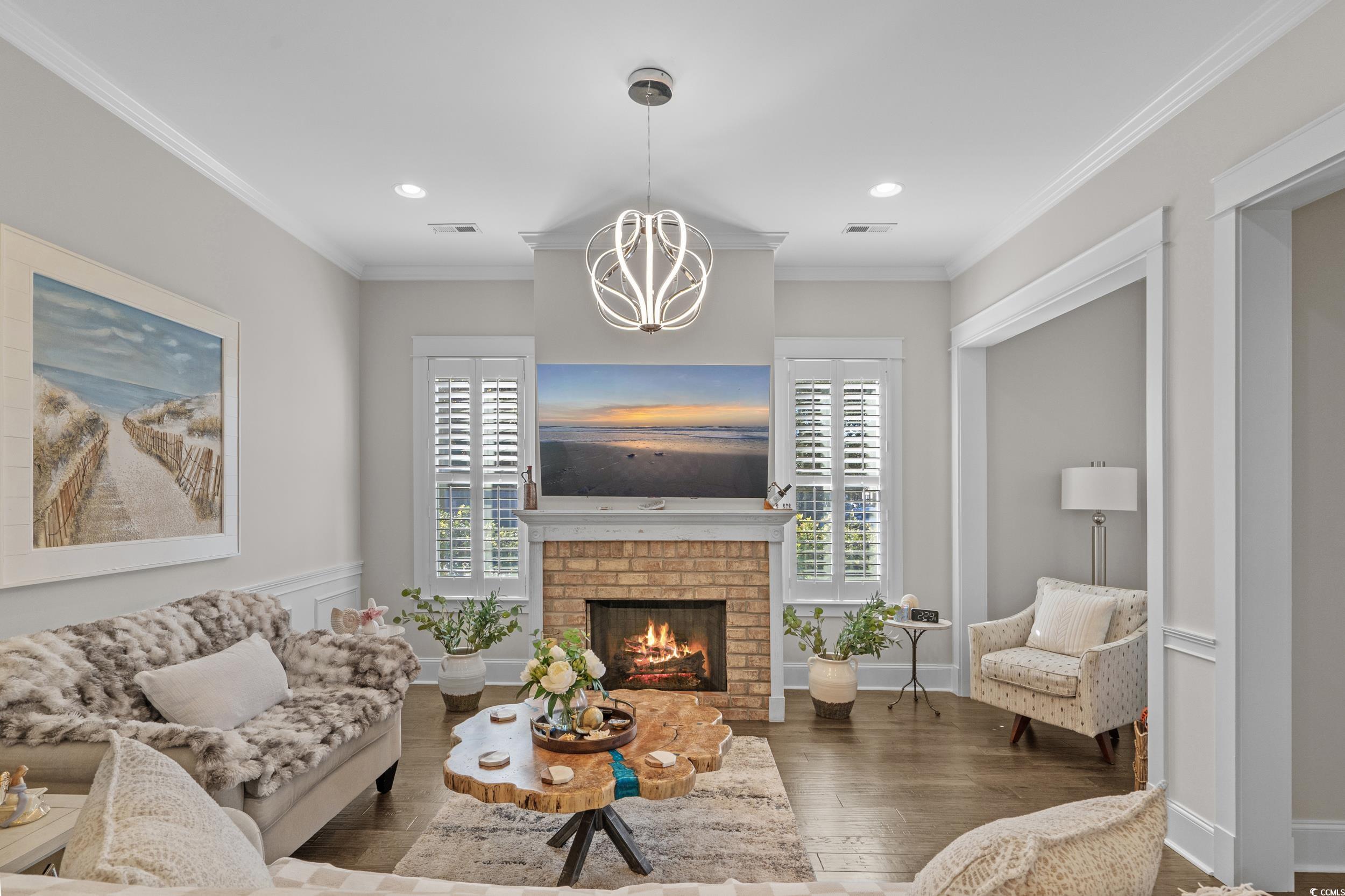 927 Iris Street Myrtle Beach, SC 29577 - Photo 9 of 40 Living area with ornamental molding, dark wood finished floors, plenty of natural light, a fireplace, and a chandelier