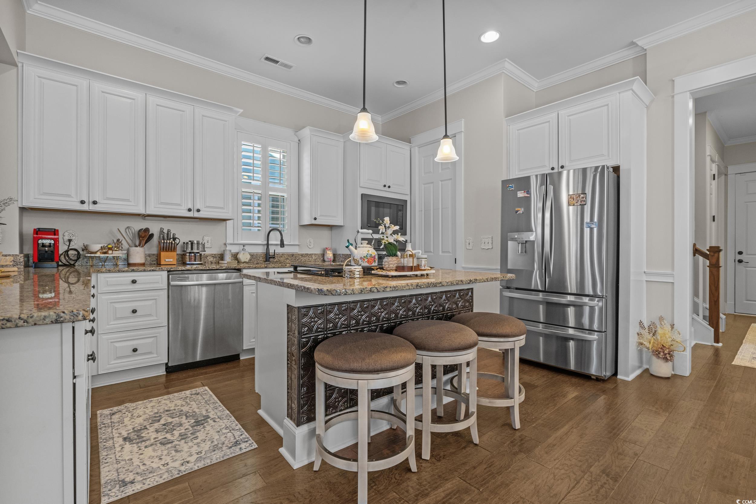 927 Iris Street Myrtle Beach, SC 29577 - Photo 10 of 40 Kitchen with a breakfast bar, light stone countertops, stainless steel appliances, a center island, and crown molding