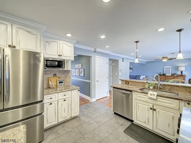 a kitchen with stainless steel appliances granite countertop a sink a stove a refrigerator and cabinets